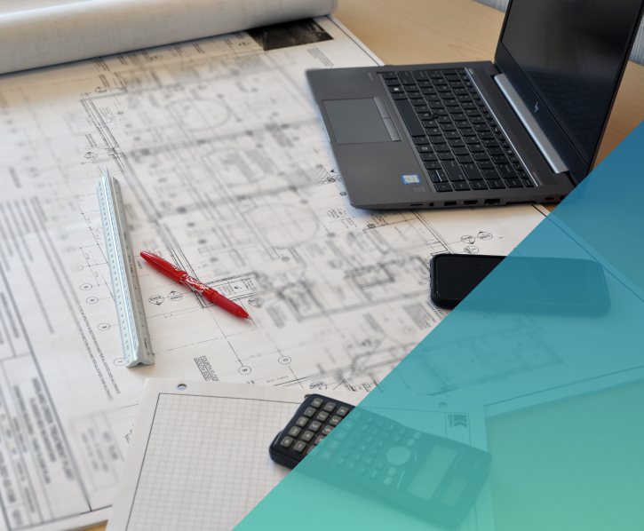 office desk with a laptop, architectural blueprint, calculator and ruler